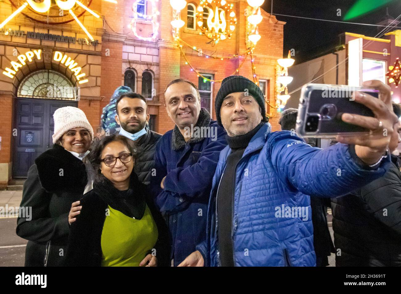 Das jährliche Diwali-Licht schaltet sich in Leicester ein. Tausende von Menschen strömen entlang der Belgrave Road in die Golden Mile in Leicester, um den Beginn des Festivals zu feiern. Das Festival ist eines der größten Diwali-Festivals in Europa. Eine Familie nimmt ein Selfie-Portrait vor dem Belgrave Center auf. Stockfoto