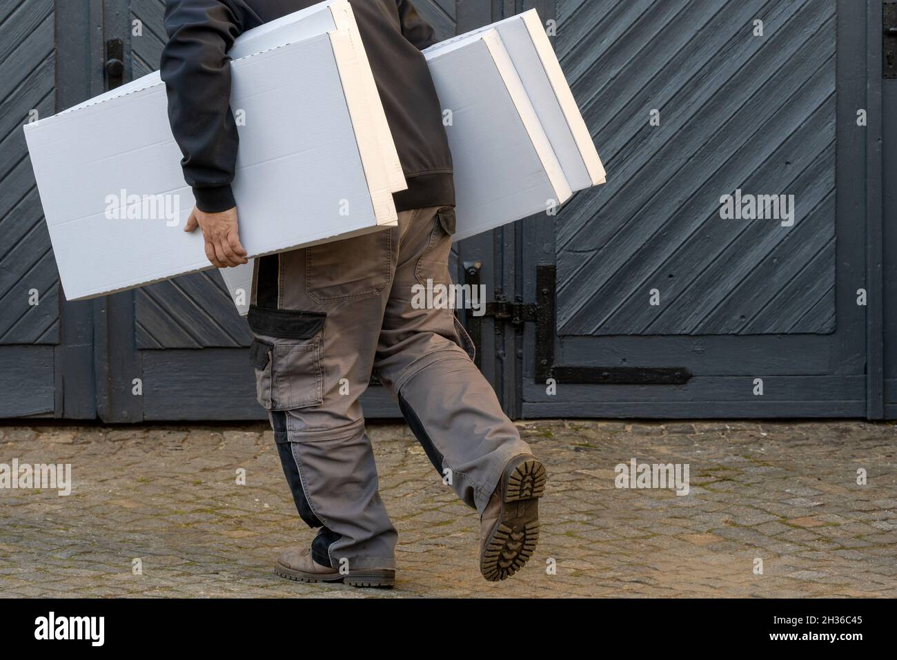 Mann läuft, hält Stapel von Kisten, Seitenansicht Stockfoto