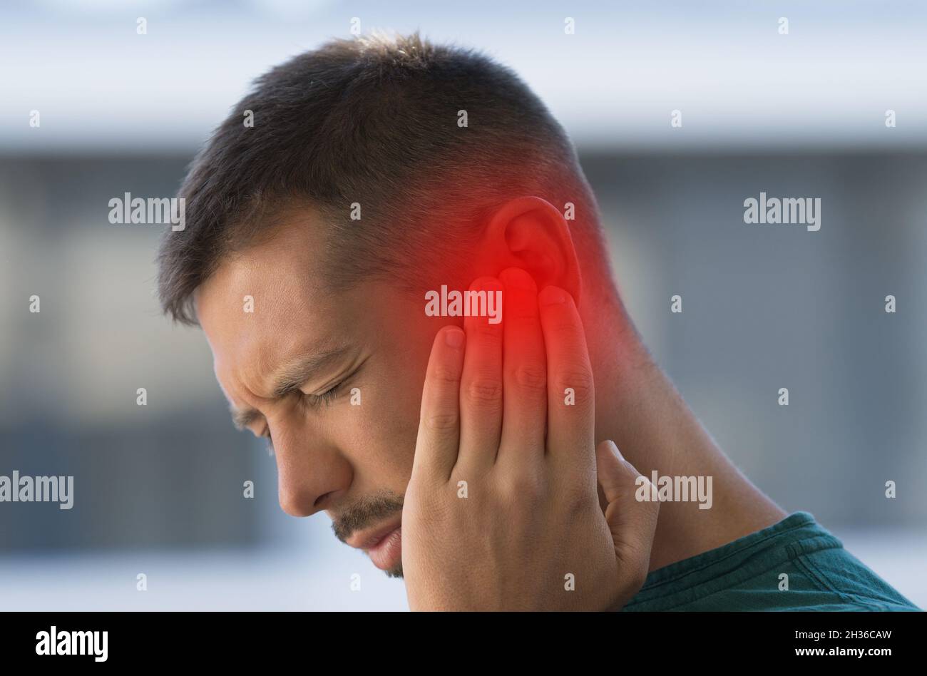 Mann, der an starken Ohrenschmerzen oder Ohrschmerzen leidet. Ohrentzündung, Otitis oder Tinnitus Stockfoto