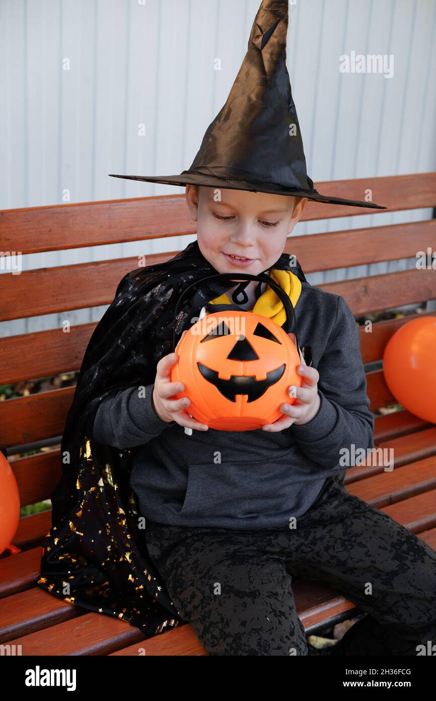 Halloween Kinder. Niedlicher kleiner Junge, Kind trägt Hexenhut mit orangefarbenem Bonbon-Eimer Jack O Lantern. Frohe Halloween. Stockfoto