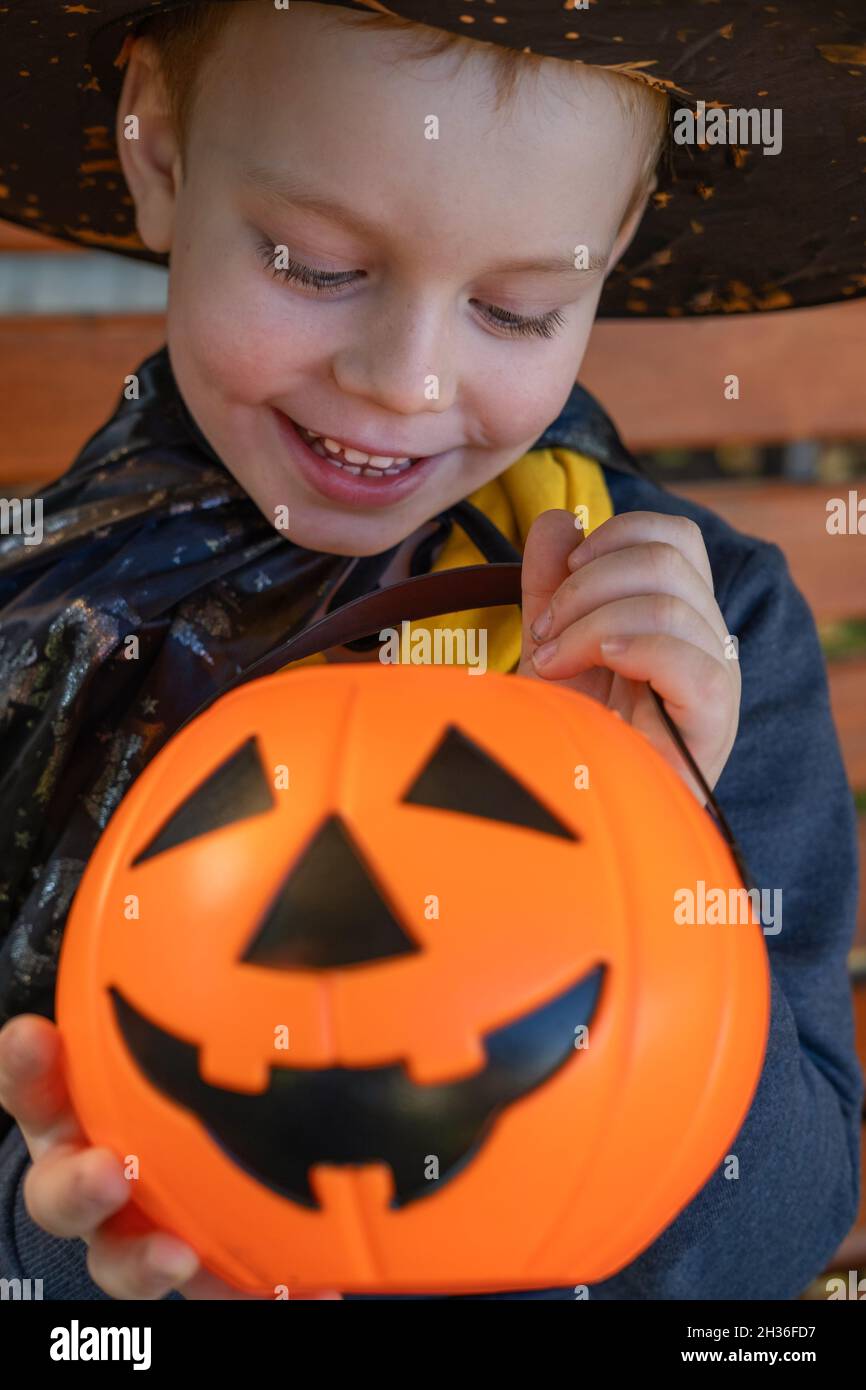Halloween Kinder. Niedlicher kleiner Junge, Kind trägt Hexenhut mit orangefarbenem Bonbon-Eimer Jack O Lantern. Frohe Halloween. Stockfoto
