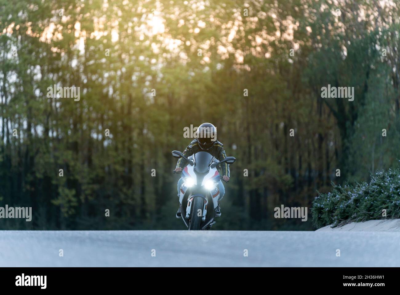 Mann, der ein großes Motorrad auf einer leeren Straße fährt Stockfoto