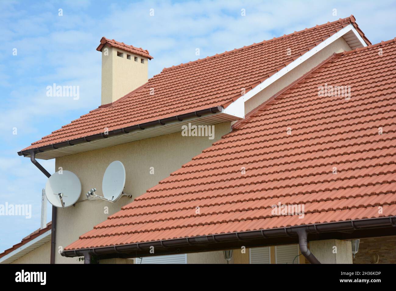 Dachkonstruktion. Haus mit rotem Lehm gekacheltem Dach und Giebel- und Taldachkonstruktion. Stockfoto