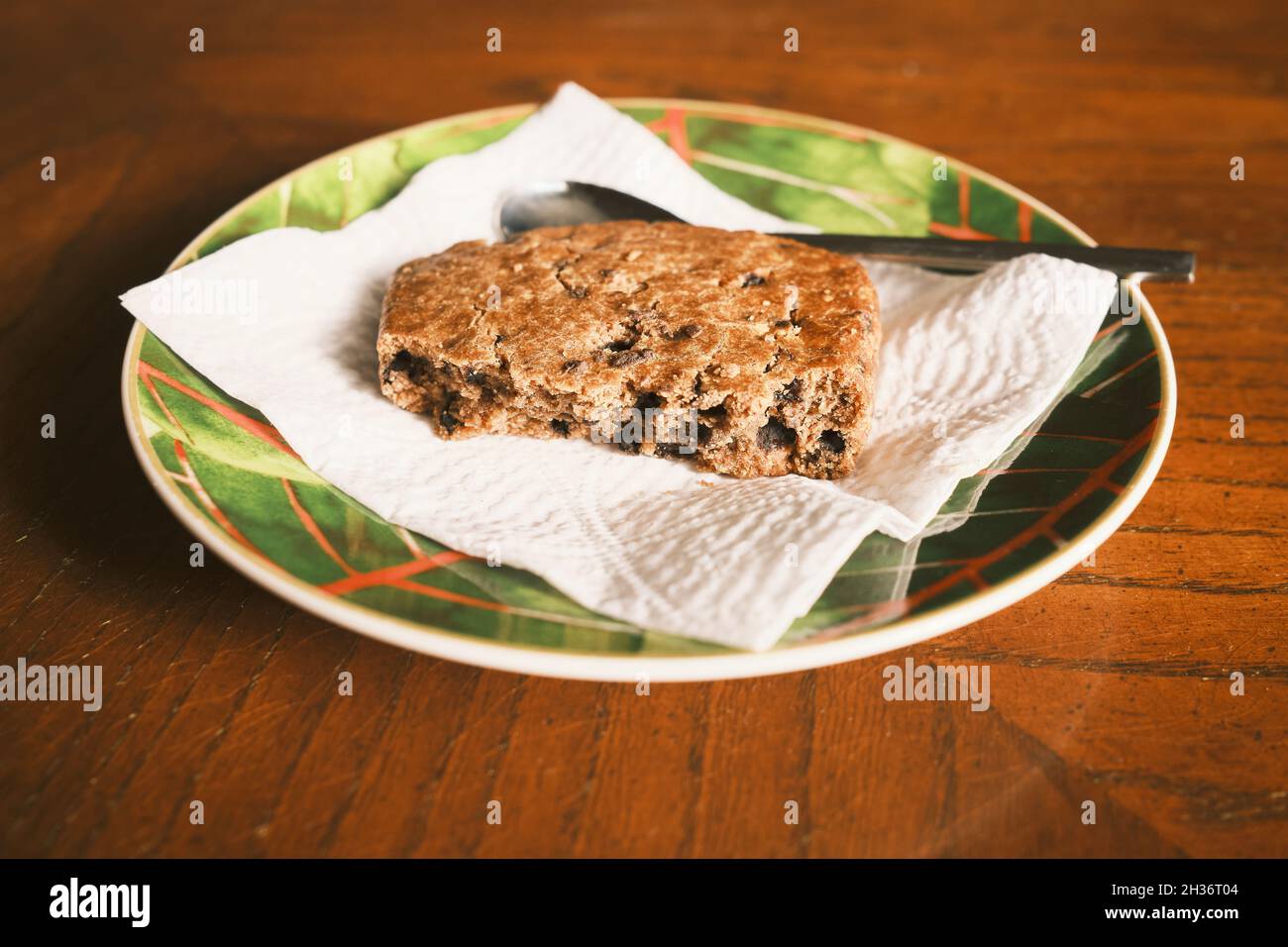 Ein Stück Kuchen auf einem Papiertuch in einem Teller, mit einem kleinen Löffel. Stockfoto