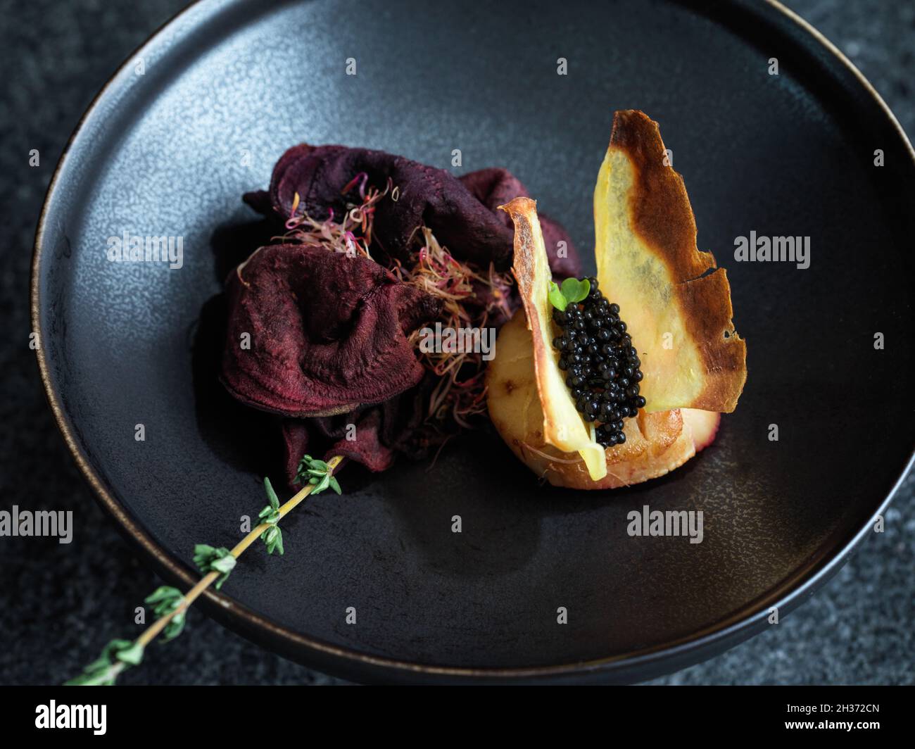 Jakobsmuschel mit Schmetterlingen wie Kartoffelchip Flügel und Kaviar mit einer Rose aus dünn geschnittener Rübenwurzel und Thymian Stockfoto