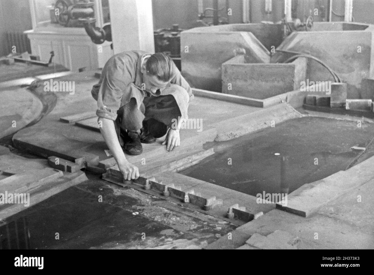 Im Flußbau Laboratorium in Karlsruhe wird ein Modell eines Staudamms durch einen Modellbauer modelliert, Deutschland 1930er Jahre. Am Fluss Engineering Laboratory in Karlsruhe ein Modell eines Flusses Schwall von einem Modellbauer konstruiert wird, Deutschland 1930. Stockfoto