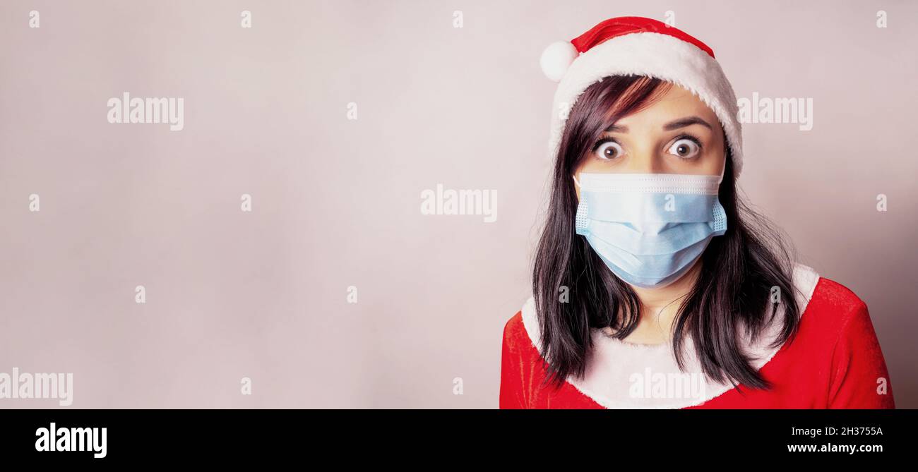 Brunette in weihnachtshut und Schutzmaske mit prall gefüllten Augen Blick auf die Kamera. Stockfoto