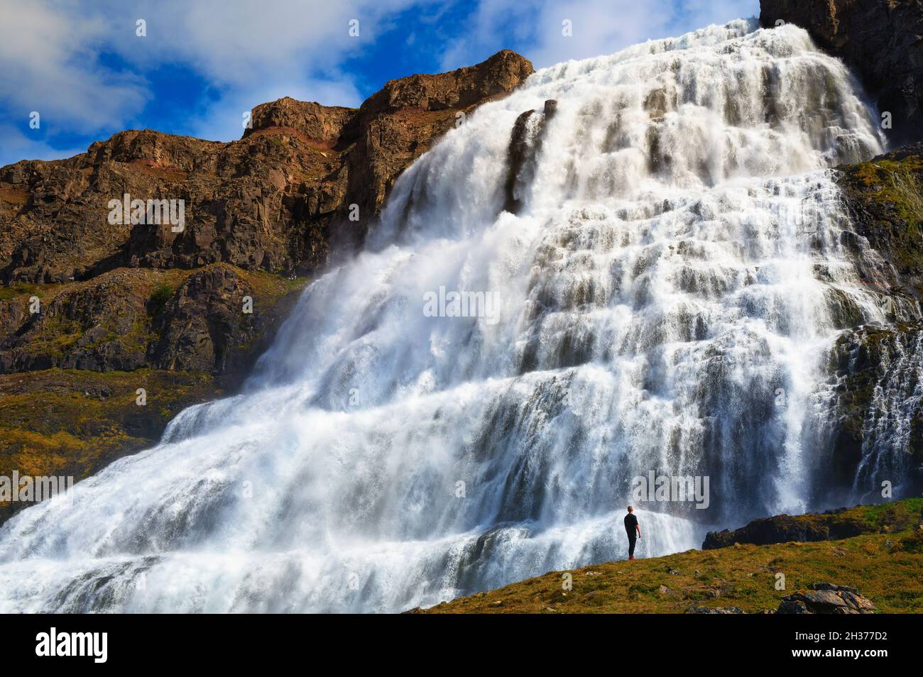 Person, die am Wasserfall Dynjandi auf der Halbinsel Westfjorde in Island steht Stockfoto