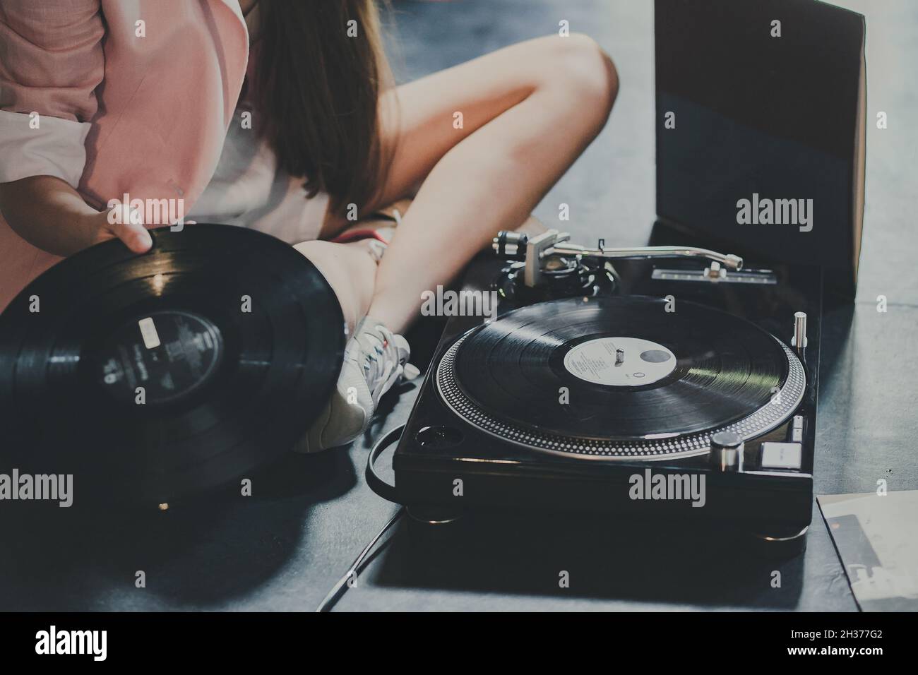 Weibliche Hände verwenden Retro-Vinyl-Player auf einem blau-rosa Pastellhintergrund. DJ. Draufsicht Stockfoto