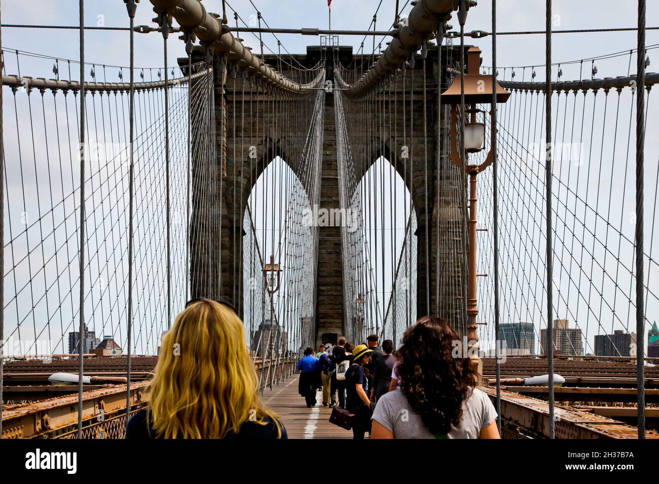 NEW YORK, NY, USA - 27. APRIL 201: Touristen wandern auf der belebten Brooklyn Bridge auf Manhattan. Stockfoto