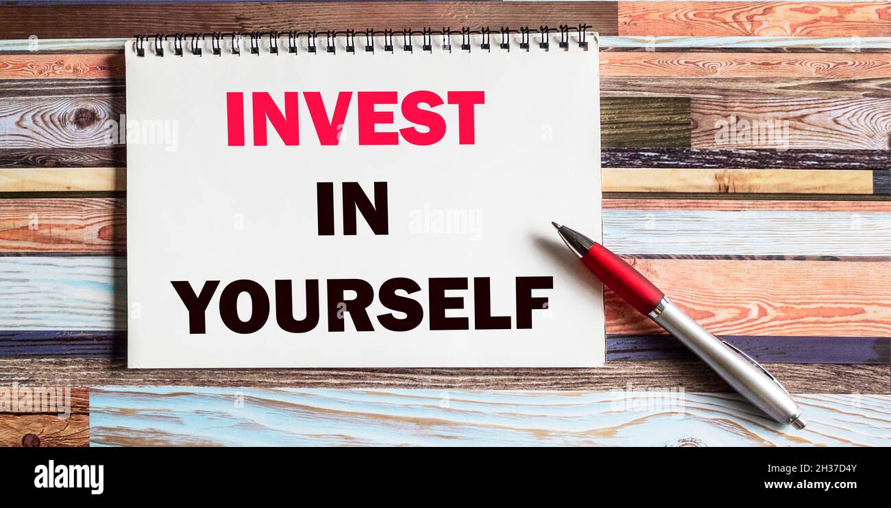 Geschäftskonzept. Notizblock mit dem Text INVESTIEREN SIE IN SICH Blatt weißes Papier für Notizen, Stift, auf einem farbigen Hintergrund Stockfoto