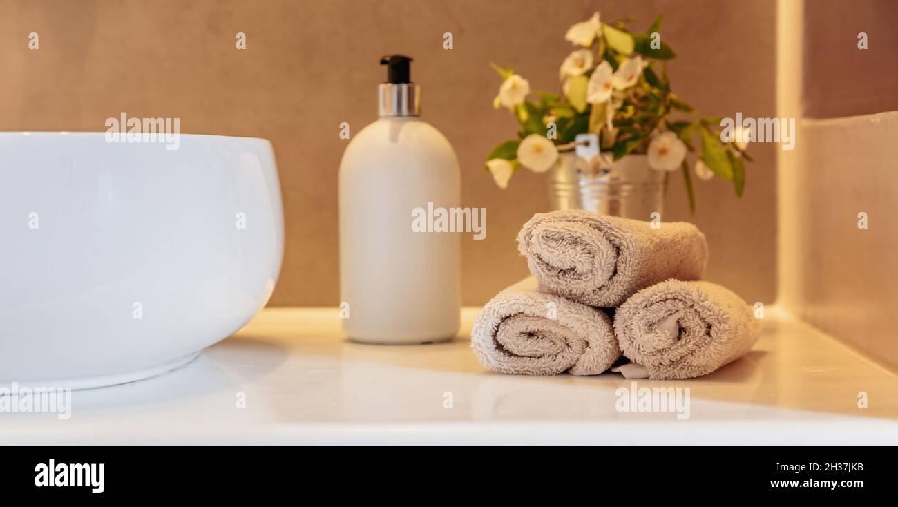 Handtücher Rollen auf, Seifenspender und weißes Waschbecken auf einem Tisch, Banner. Moderne Inneneinrichtung im Bad. Stockfoto