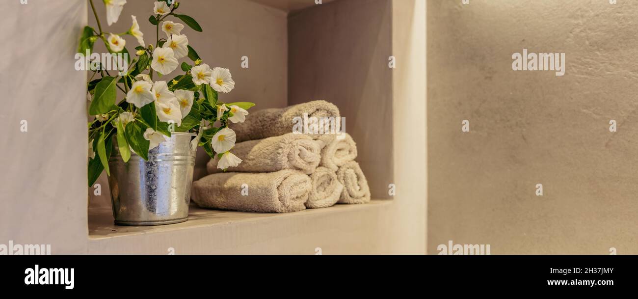 Badezimmer mit moderner Innenausstattung. Frische blühende Pflanze und Handtücher auf einem Regal gestapelt. Leerer Raum, Vorlage für Spa-Wellness-Zimmer Stockfoto
