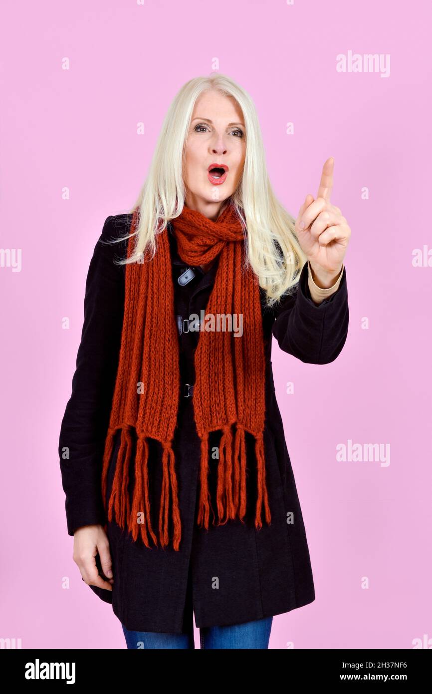 Attraktive Blonde Lady auf rosa Hintergrund mit der Hand nach oben und einem Finger nach oben und Mund in O-Form aufgenommen. Konzept absprechen Stockfoto