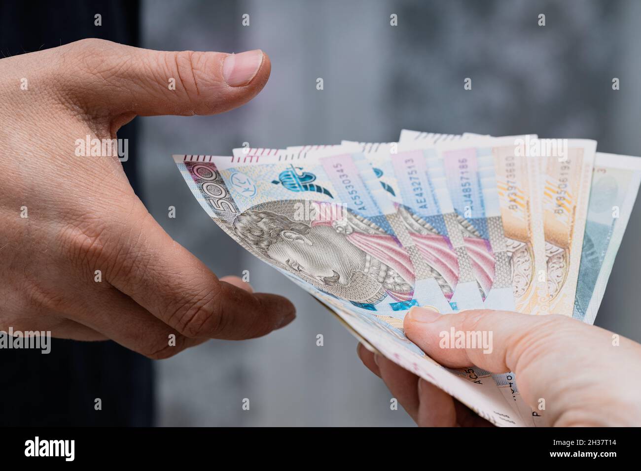 Polnisches Geld, Eine Akte von 500 und 200 Zloty-Banknoten, die von Hand zu Hand an eine andere Person übertragen wurden Stockfoto