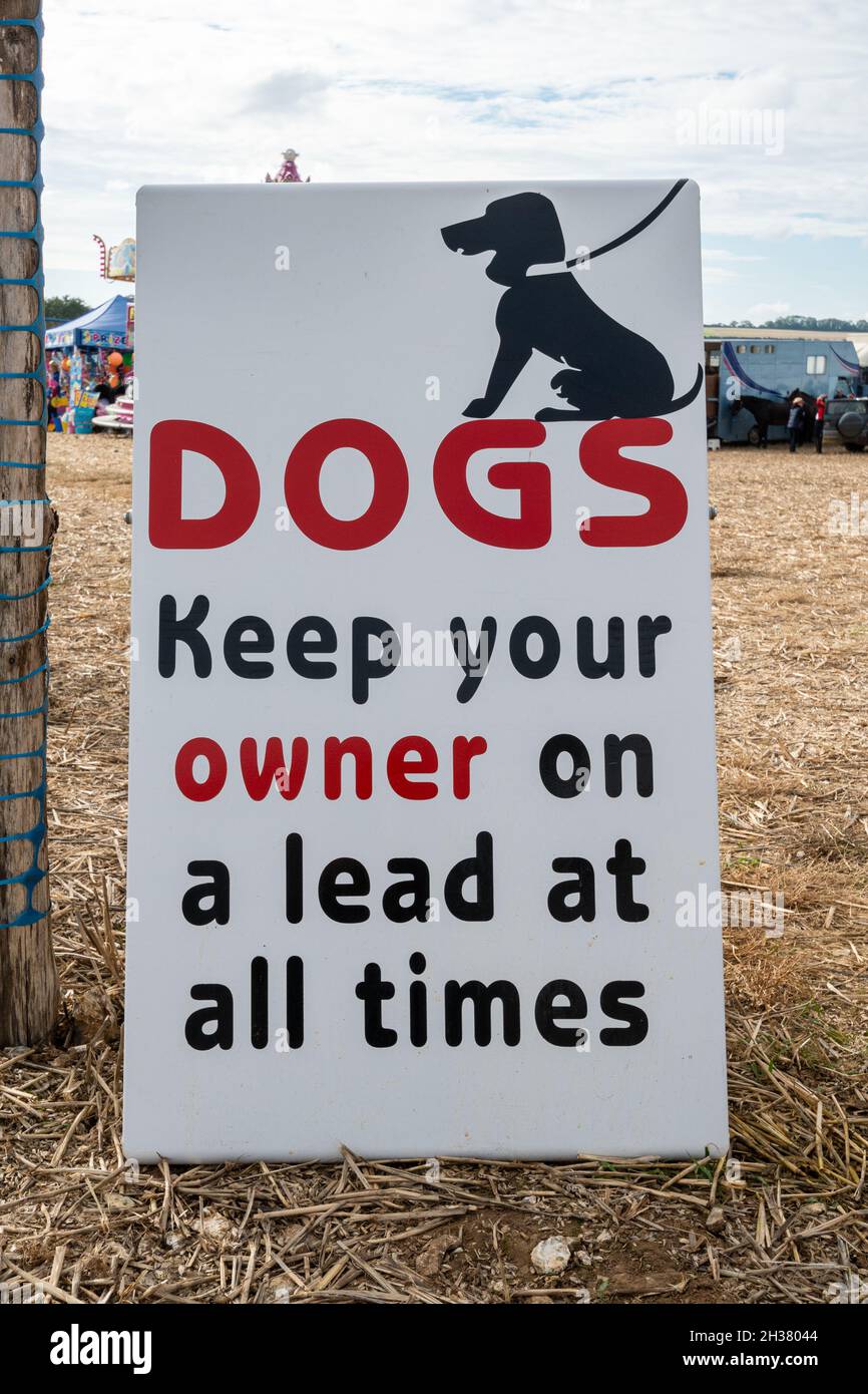 Zeichen lesen Hunde Halten Sie Ihren Besitzer immer an der Leine. Amüsantes, humorvolles Zeichen bei einem Pferderennen, Großbritannien Stockfoto