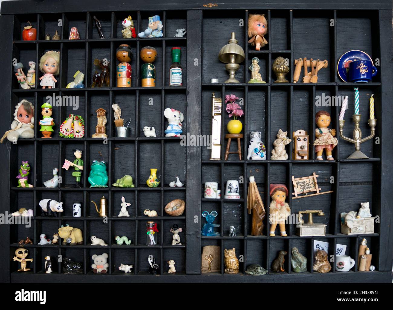 Set aus Schnickschnack, Miniaturen, Souvenirs und Sammlerstücken auf einem Holzregal an der Wand in einem Haus. Stockfoto