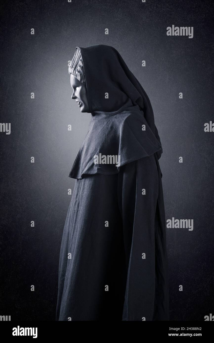 Frauengeist im Kapuzenmantel über dunklem nebligen Hintergrund Stockfoto