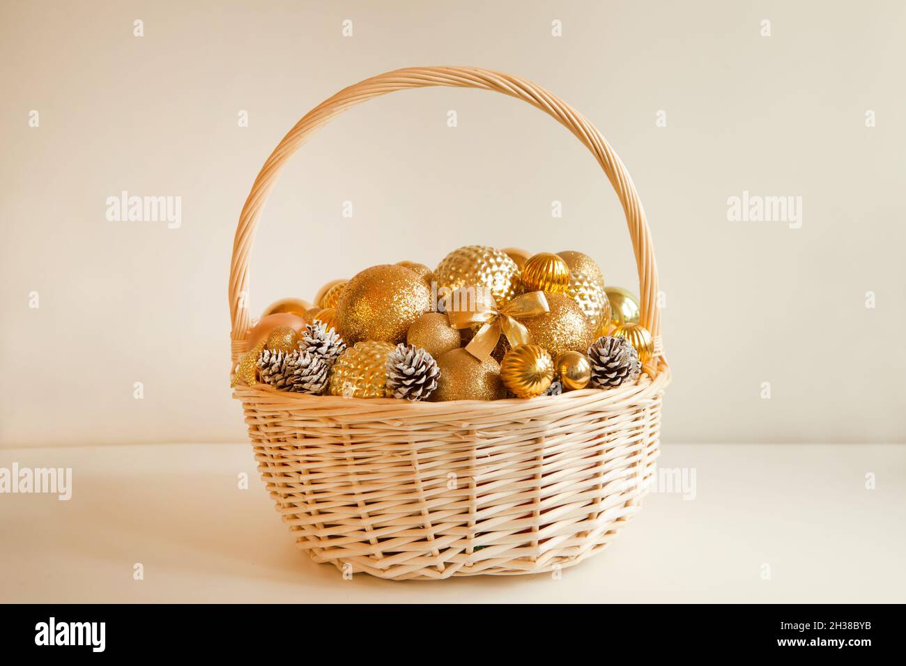 Riesiger Korbkorb, gefüllt bis an die Spitze mit goldenen Kugeln, um Weihnachtstanne oder Wohnung zu schmücken Stockfoto
