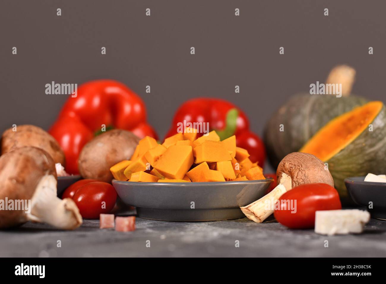 Zutaten zum Kochen mit Kürbis, Pilzen, Paprika, Tomaten, roten Zwiebeln, Speck und Feta-Käse Stockfoto