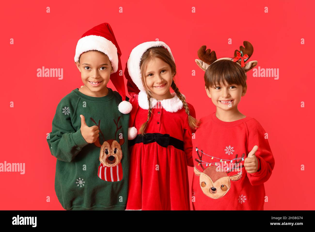 Kleine Kinder in Weihnachtskleidung auf rotem Hintergrund Stockfotografie -  Alamy