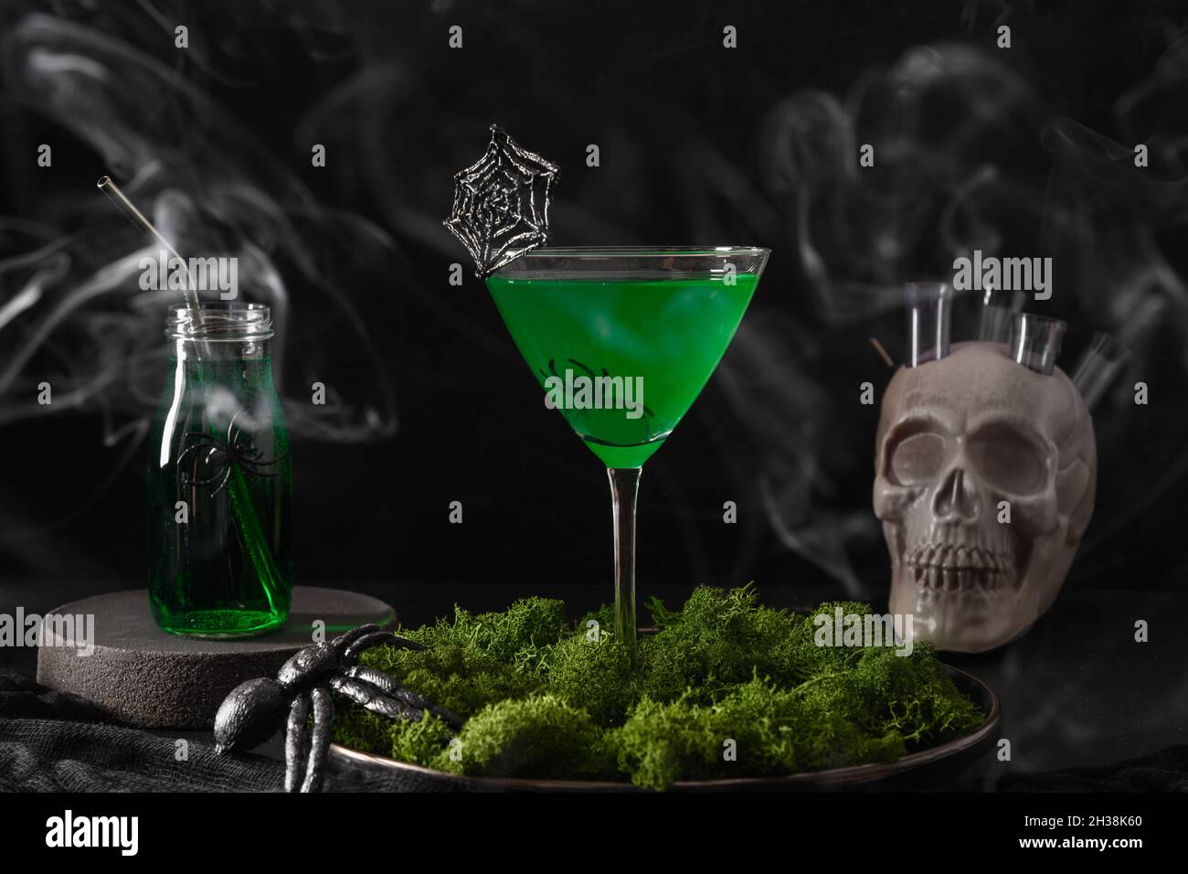 Halloween grüne Cocktails mit Totenköpfen, Spinnen und Rauch auf schwarzem Hintergrund. Horror lustiges Essen. Stockfoto