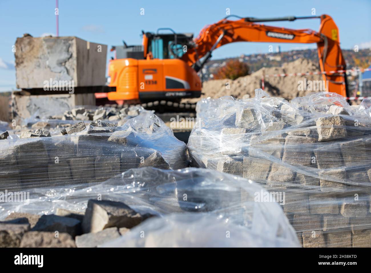 Nahaufnahme der Baustelle, des orangefarbenen Greifers und der Betonsteine Stockfoto