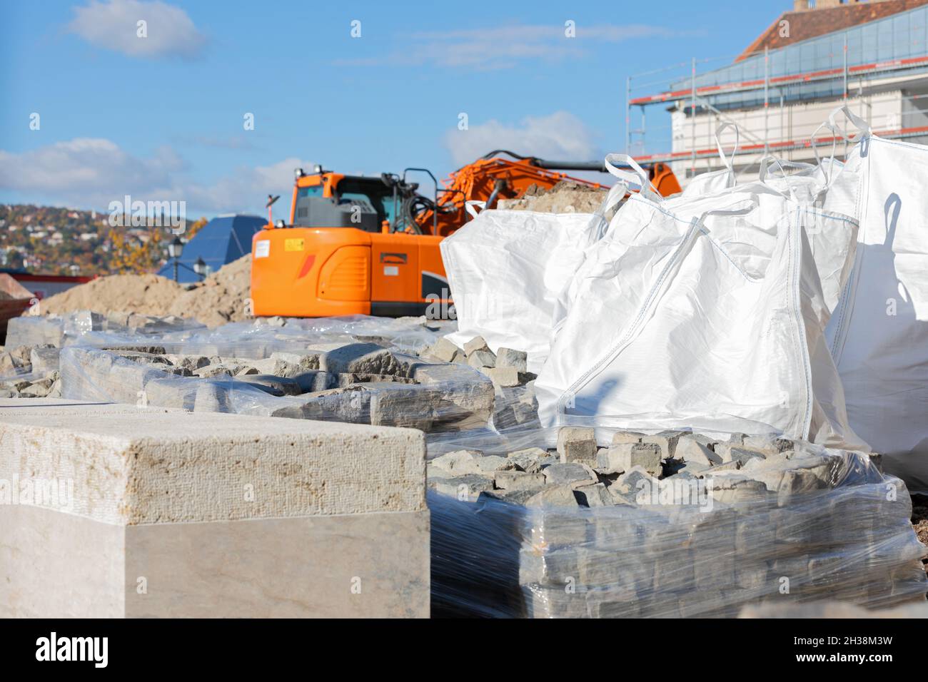 Nahaufnahme der Baustelle, des orangefarbenen Greifers und der Betonsteine Stockfoto