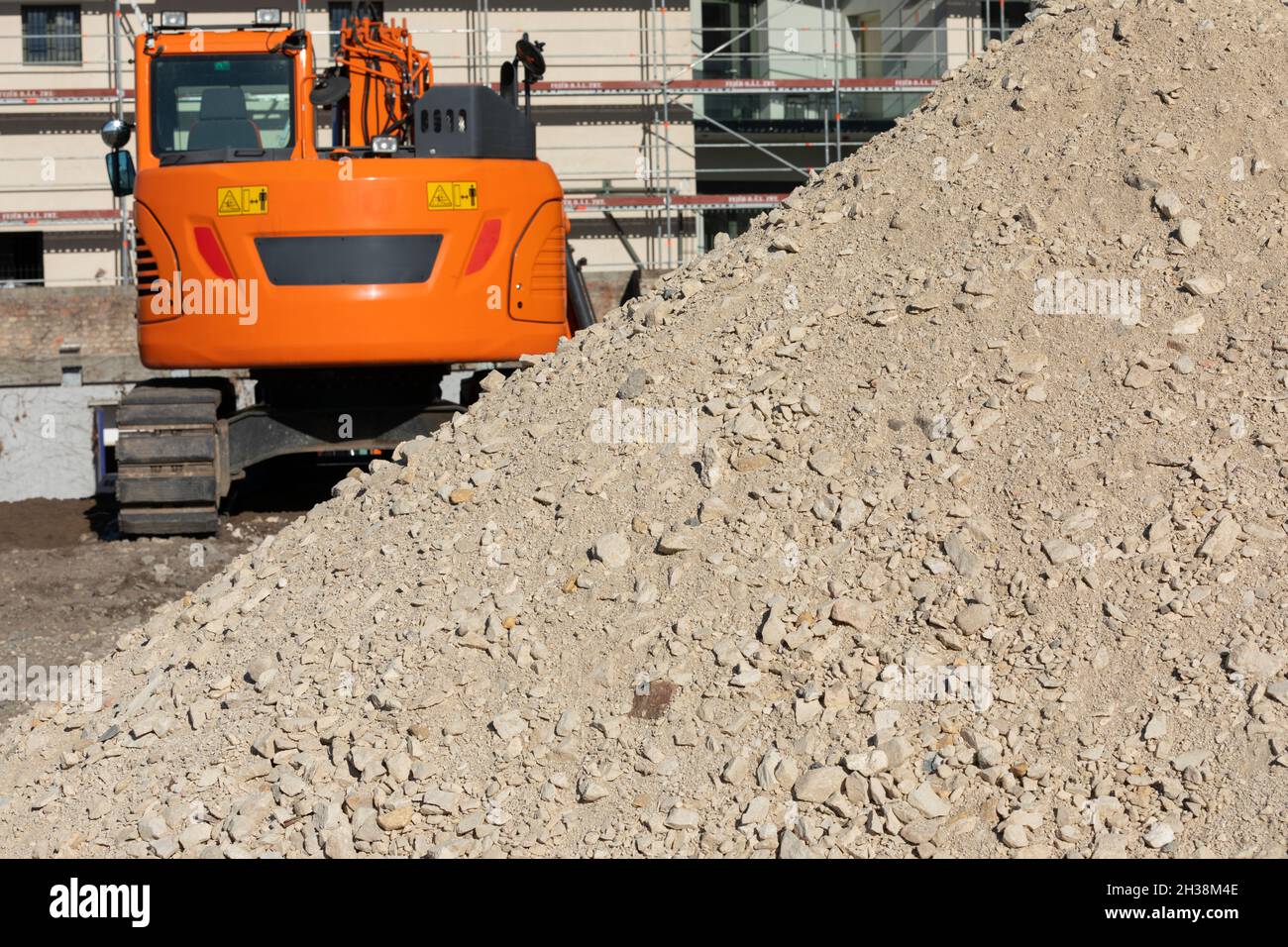Nahaufnahme der Baustelle, des orangefarbenen Greifers und der Betonsteine Stockfoto