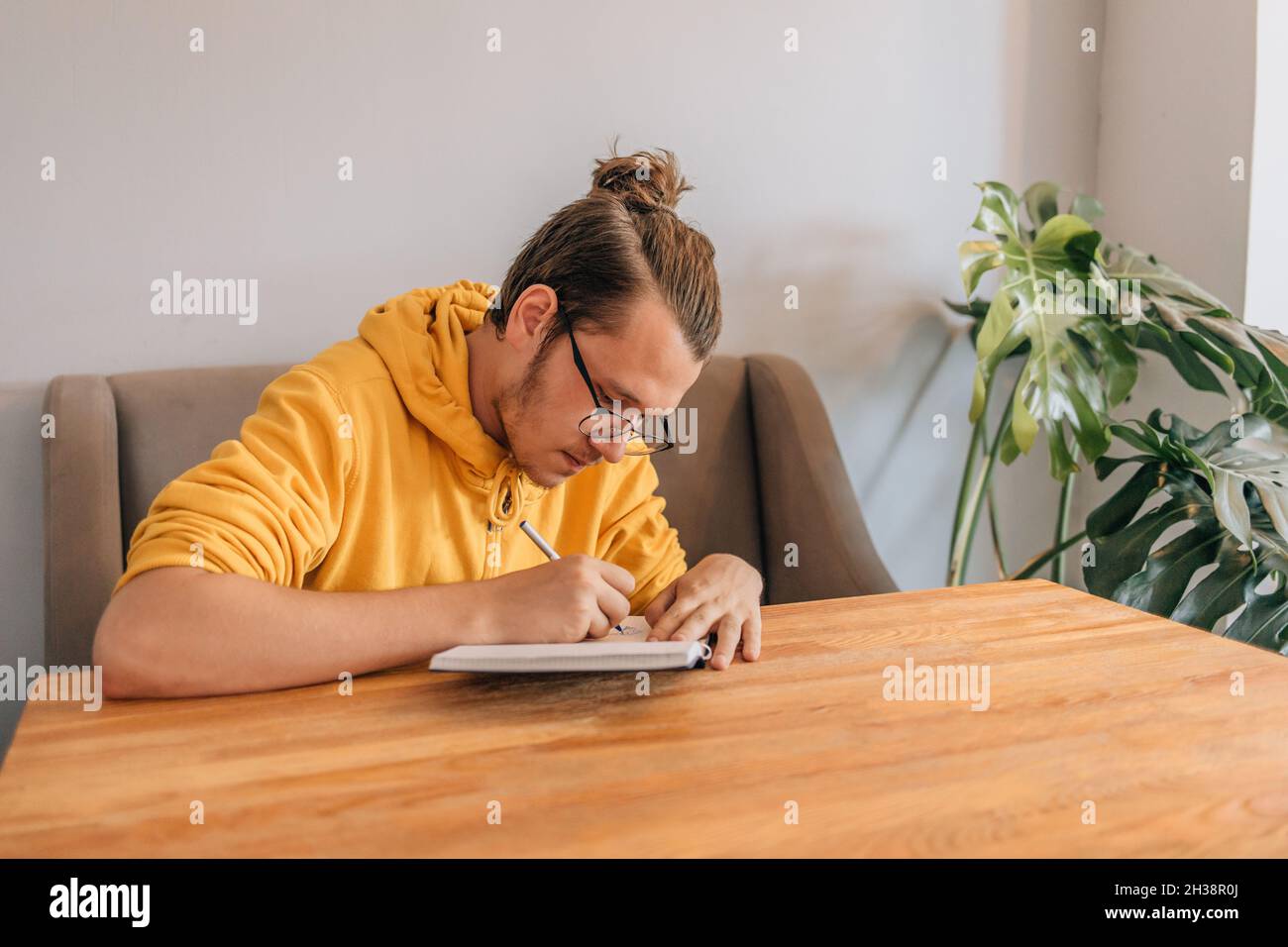 Teenager junger Mann schreibt im Café in einem Notizbuch. Lifestyle-Aufnahme. Stockfoto