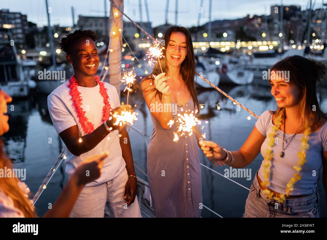Gruppe von Menschen, die Spaß haben und Neujahr mit Wunderkerzen auf einem Boot feiern - Happy Lifestyle Konzept - Fokus auf afrikanischen Mann Stockfoto