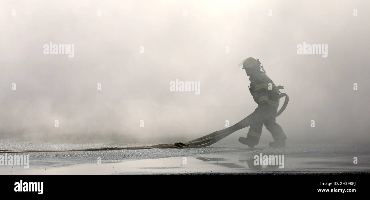 Ein Feuerwehrmann mit dem Logcap V Emergency Services Directorate (ESD) Fire & Emergency Services bereitet im Lager Buehring, Kuwait, einen Feuerwehrschlauch für ein Training mit einem simulierten abgestürzte Flugzeug mit simulierten verletzten Soldaten vor. Stockfoto