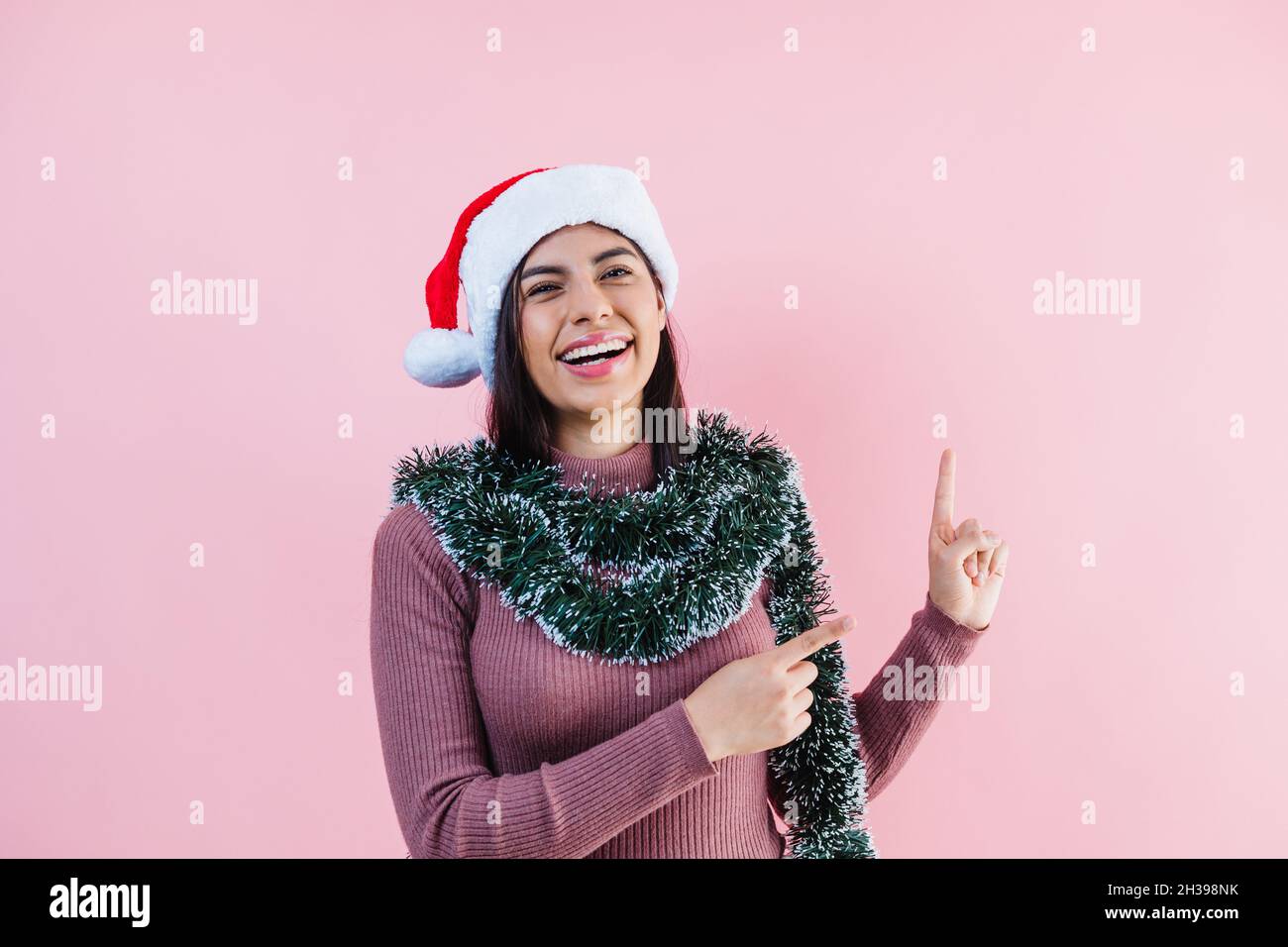 Porträt einer jungen latinerin mit Kopierfläche in einem weihnachtskonzept auf rosa Hintergrund Stockfoto