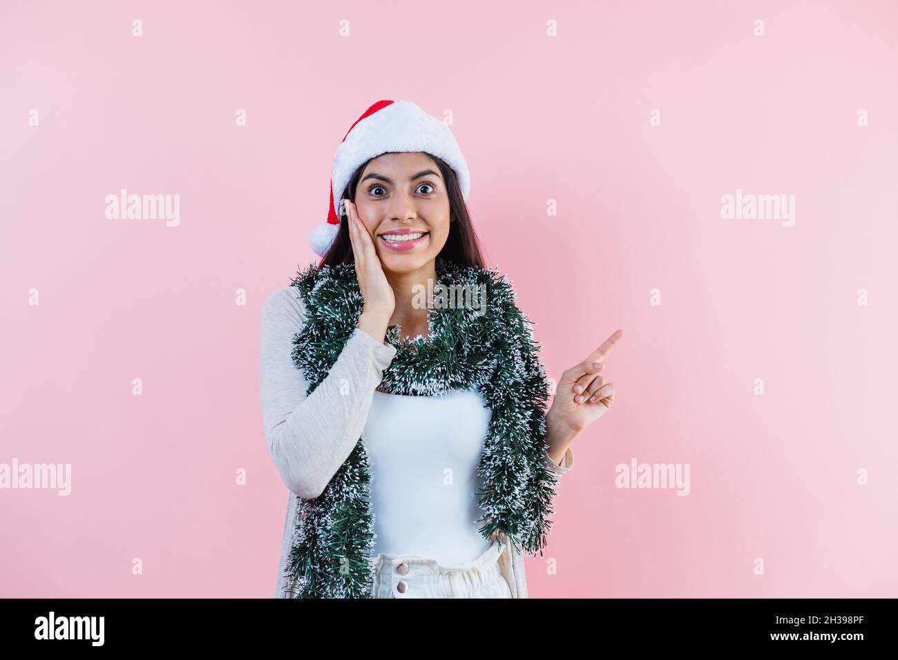 Porträt einer jungen latinerin mit Kopierfläche in einem weihnachtskonzept auf rosa Hintergrund Stockfoto