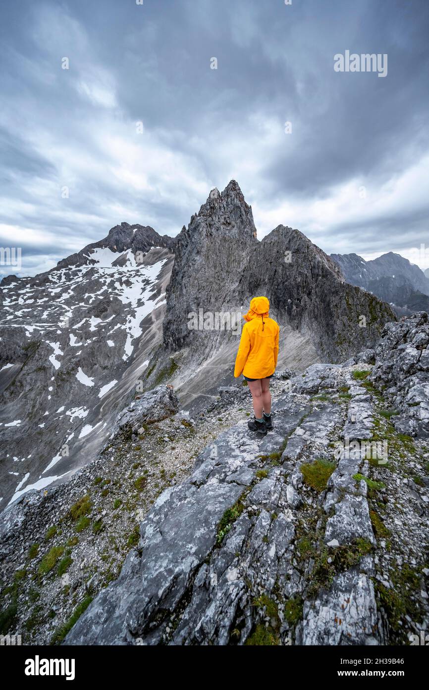Wanderer, die Berge unter dramatischen Wolken betrachten, Blick vom Gipfel der westlichen Toerlspitze, hinten Partenkirchner Dreiterspitze Stockfoto