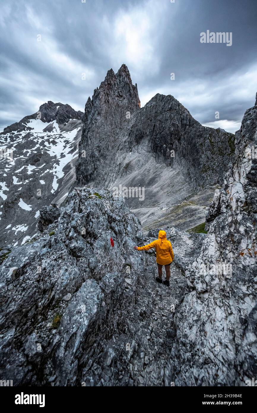 Wanderer, die Berge unter dramatischen Wolken betrachten, Blick vom Gipfel der westlichen Toerlspitze, hinten Partenkirchner Dreiterspitze Stockfoto