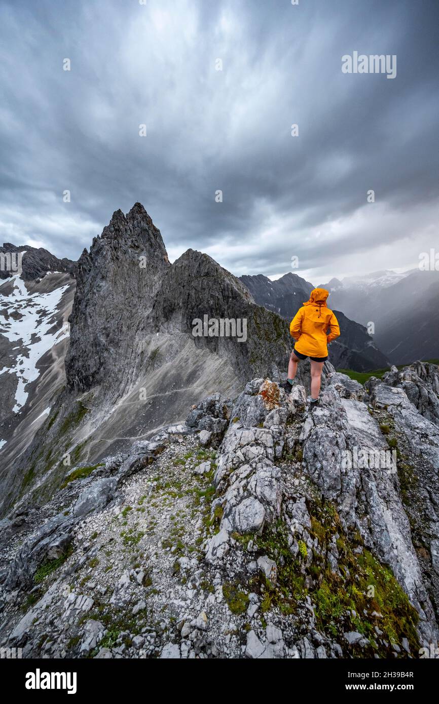 Wanderer, die Berge unter dramatischen Wolken betrachten, Blick vom Gipfel der westlichen Toerlspitze, hinten Partenkirchner Dreiterspitze Stockfoto