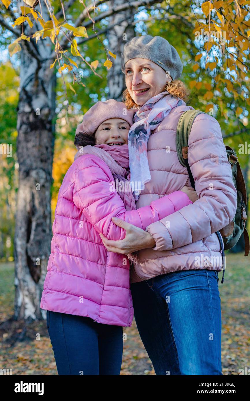 Nette und fröhlich lächelnde kaukasische Mutter und Tochter verbringen Zeit im Herbstpark. Eine glückliche Familie. Spaziergang im Park mit Kindern. Sonniger Herbsttag. P Stockfoto