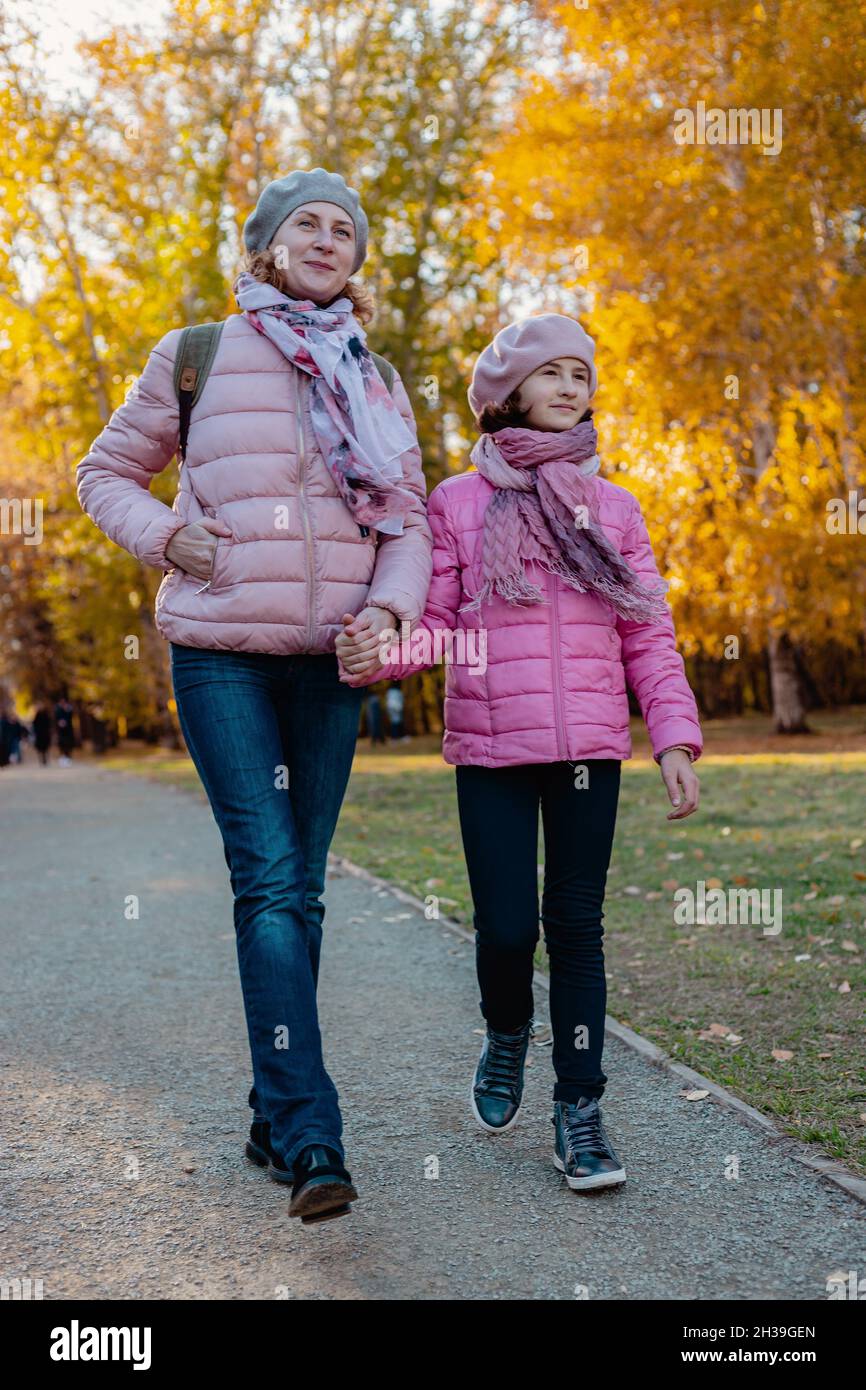 Spaziergang im Park mit Kindern. Nette und fröhlich lächelnde kaukasische Mutter und Tochter verbringen Zeit im Herbstpark. Sonniger Herbsttag. Eine glückliche Familie. P Stockfoto