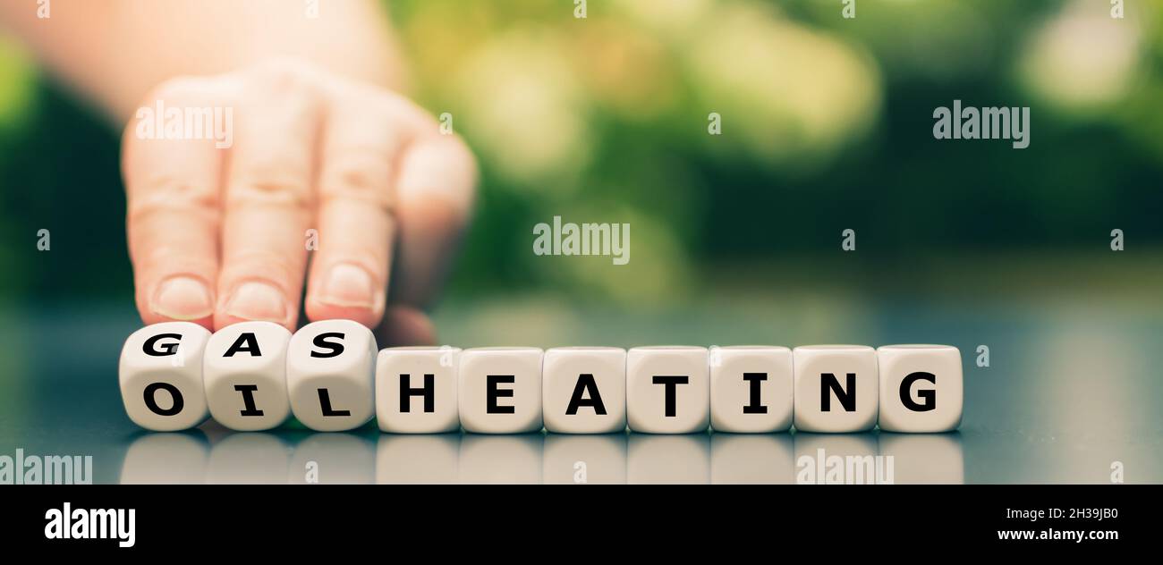Symbol für den Wechsel der Heizung. Die Hand dreht Würfel und ändert den Ausdruck „Ölheizung“ in „Gasheizung“. Stockfoto