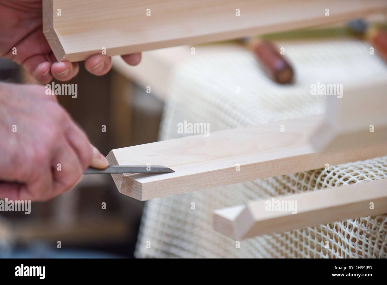 Der Mensch verwendet einen Meißel, um Holz in der Zimmerei zu Formen und zu schnitzen Stockfoto