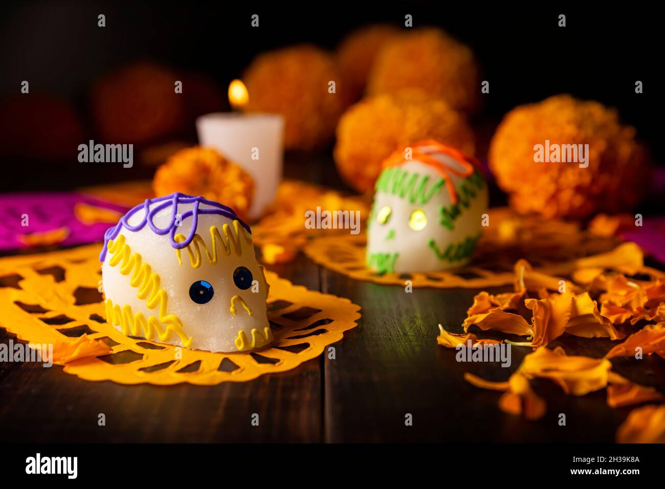 Zuckerschädel mit Kerze, Crepasuchil-Blüten oder Ringelblume und Papel Picado. Dekoration traditionell in Altären für die Feier des Tages verwendet Stockfoto