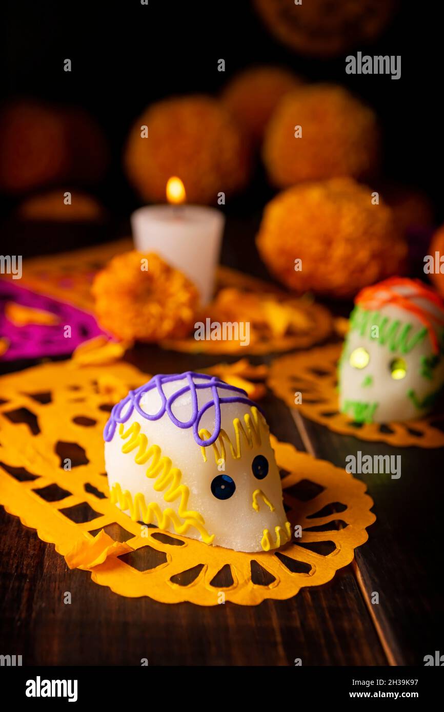 Zuckerschädel mit Kerze, Crepasuchil-Blüten oder Ringelblume und Papel Picado. Dekoration traditionell in Altären für die Feier des Tages verwendet Stockfoto
