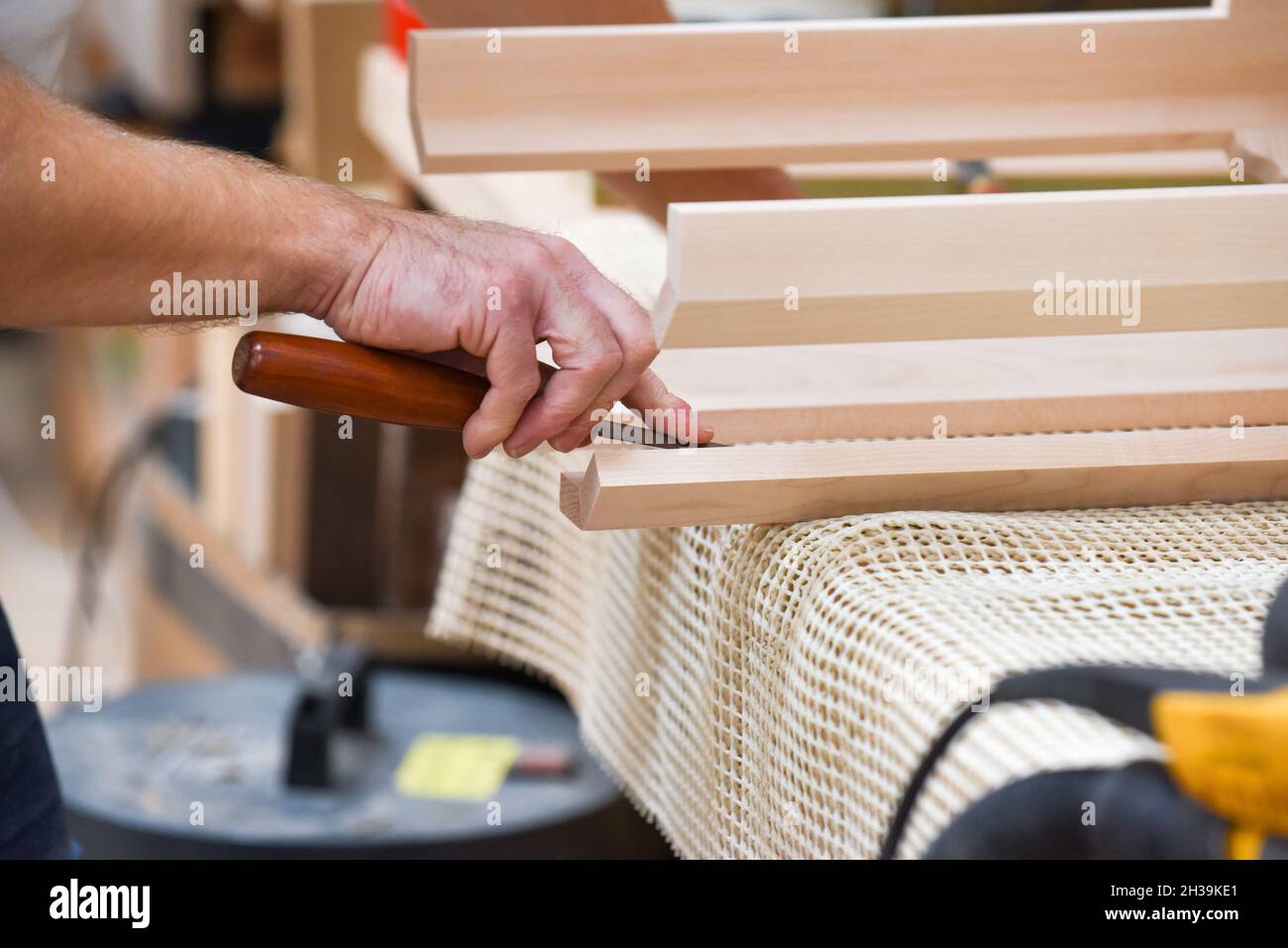 Der Mensch verwendet einen Meißel, um Holz in der Zimmerei zu Formen und zu schnitzen Stockfoto