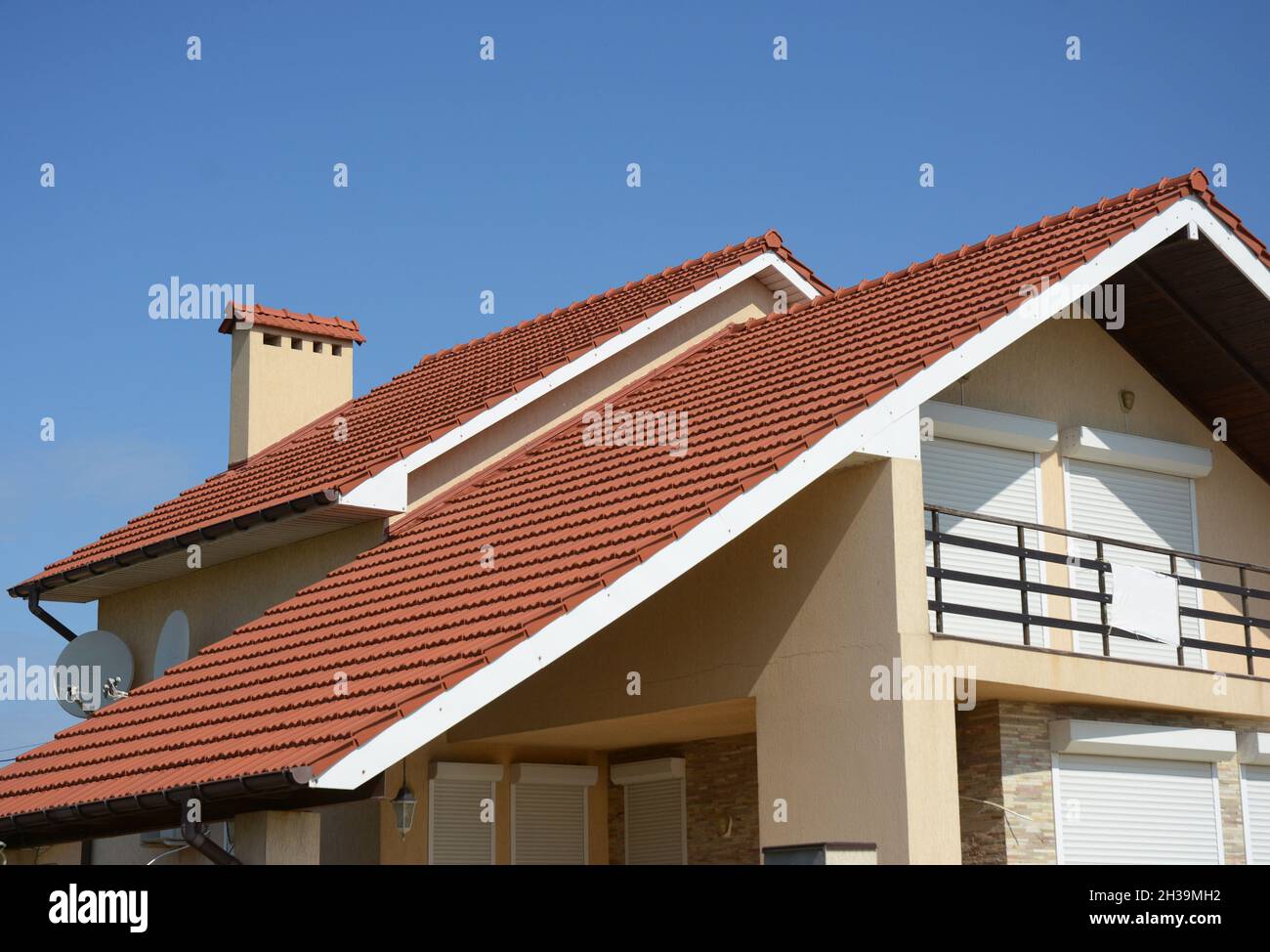 Gemütliches Haus mit Balkon, Lehm-Ziegeldach und Giebel und Tal Art der Dachkonstruktion. Gebäude Dachgeschosshausbau mit verschiedenen Arten von Roo Stockfoto