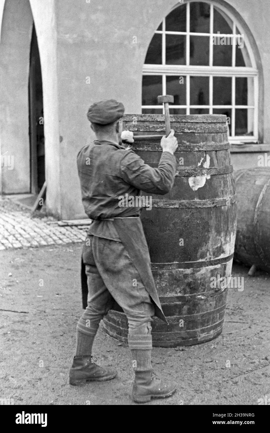 Ein Böttcher bei der Fassherstellung und Gebäude in Serrig, Deutschland 1930er Jahre. Ein cooper Bau ein Faß her die neue geernteten Wein in Serrig, Deutschland 1930. Stockfoto