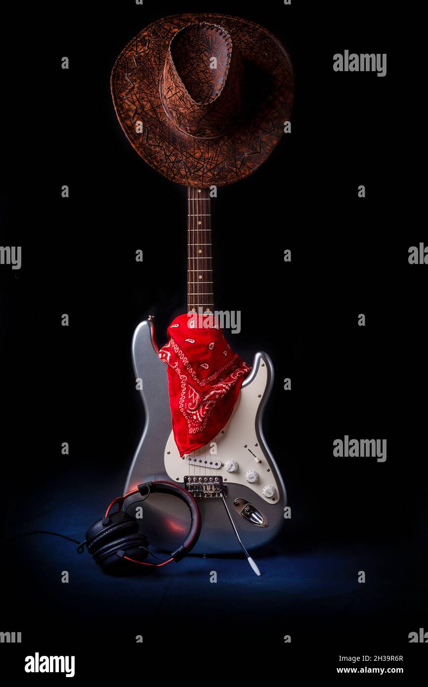 Silberne E-Gitarre mit rotem Bandana-Hut und Kopfhörern Stockfoto