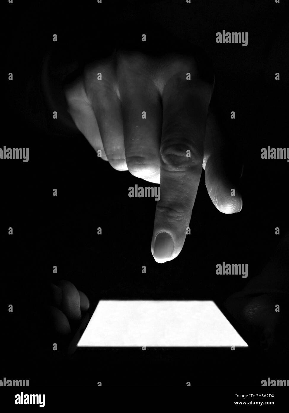 Anonymer Internetnutzer hält ein Smartphone in der Dunkelheit und tippt mit den Fingern auf den Bildschirm. Internet Crime Konzept Stockfoto