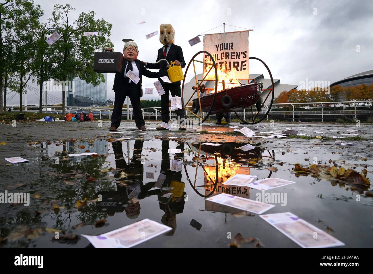 Darsteller von Ocean Rebellion, gekleidet als Premierminister Boris Johnson und ein Oilhead, zündeten das Segel eines kleinen Bootes an, auf dem „die Zukunft Ihrer Kinder“ steht, während sie Stapel Geld am Ufer des Flusses Clyde in Glasgowm in der Nähe des Standorts der kommenden Cop26 verbrennen Konferenz, die den Abbau des Ozeans hervorhebt. Die Szene stellt dar, was Rotester gesagt haben: „die britische Regierung hat keinen Sinn für die Bekämpfung des katastrophalen Klimawandels“. Bilddatum: Mittwoch, 27. Oktober 2021. Stockfoto