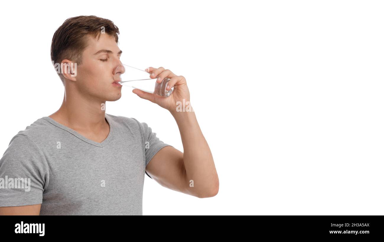 Schöner ruhiger muskulöser junger Kaukasier, der Wasser aus Glas trinkt, isoliert auf weißem Hintergrund Stockfoto